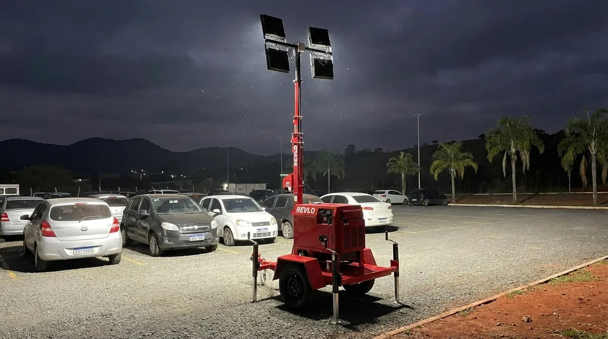 Torre de iluminação Revlo iluminando um pátio durante a noite, com a serra ao fundo